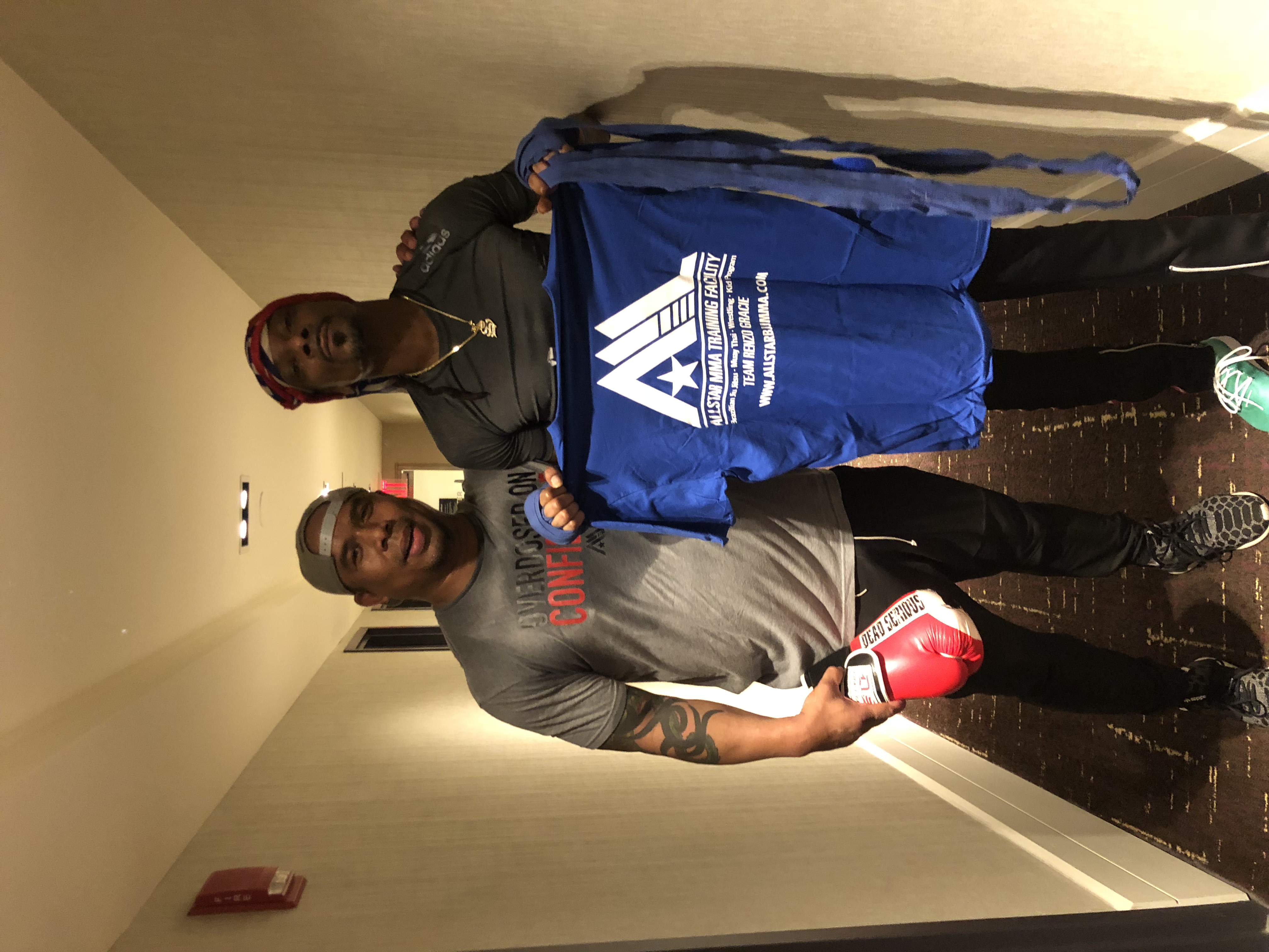 Jamal Patterson with a friend, holding up an AllStar MMA Training Facility shirt
